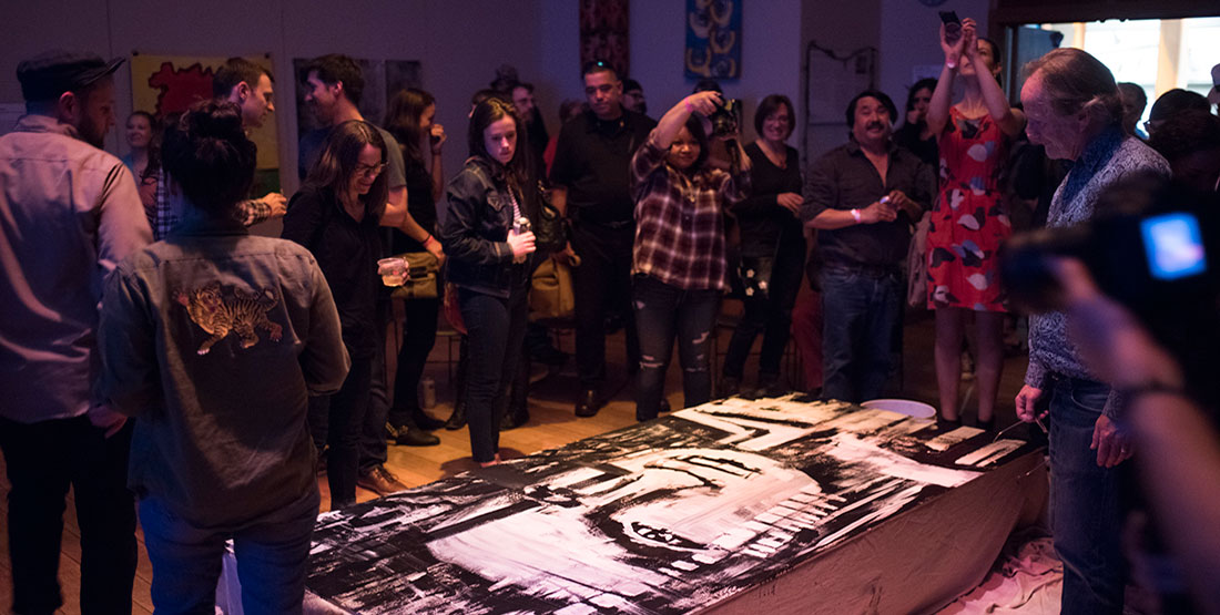 Crowd of people looking at artwork on the ground