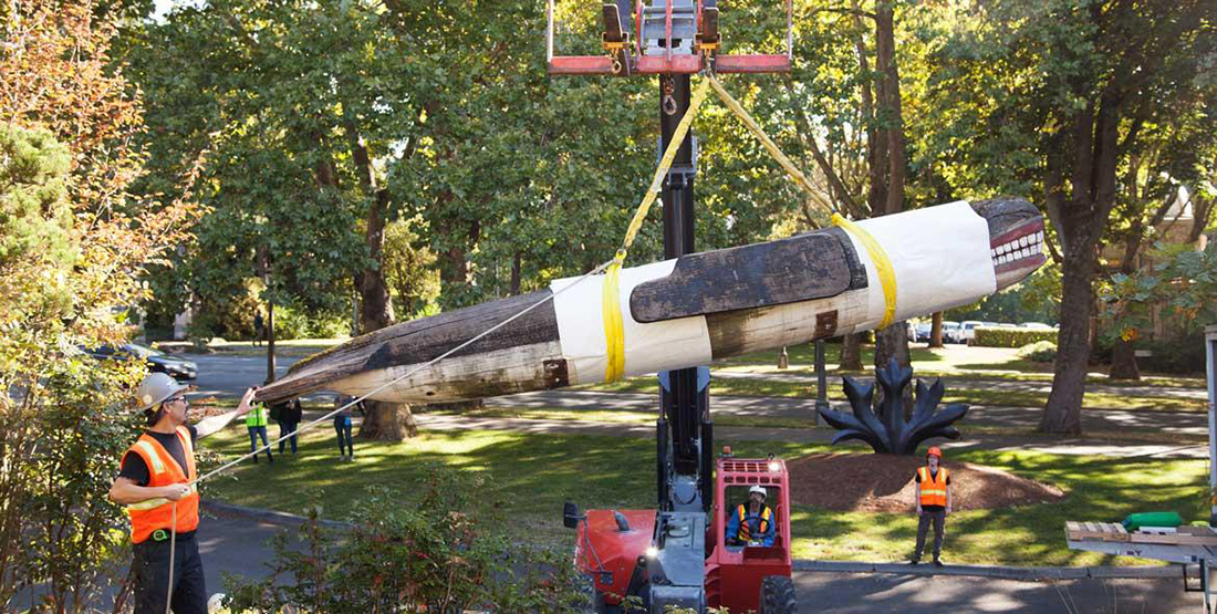 A large whale carving is carefully hoisted by a crane