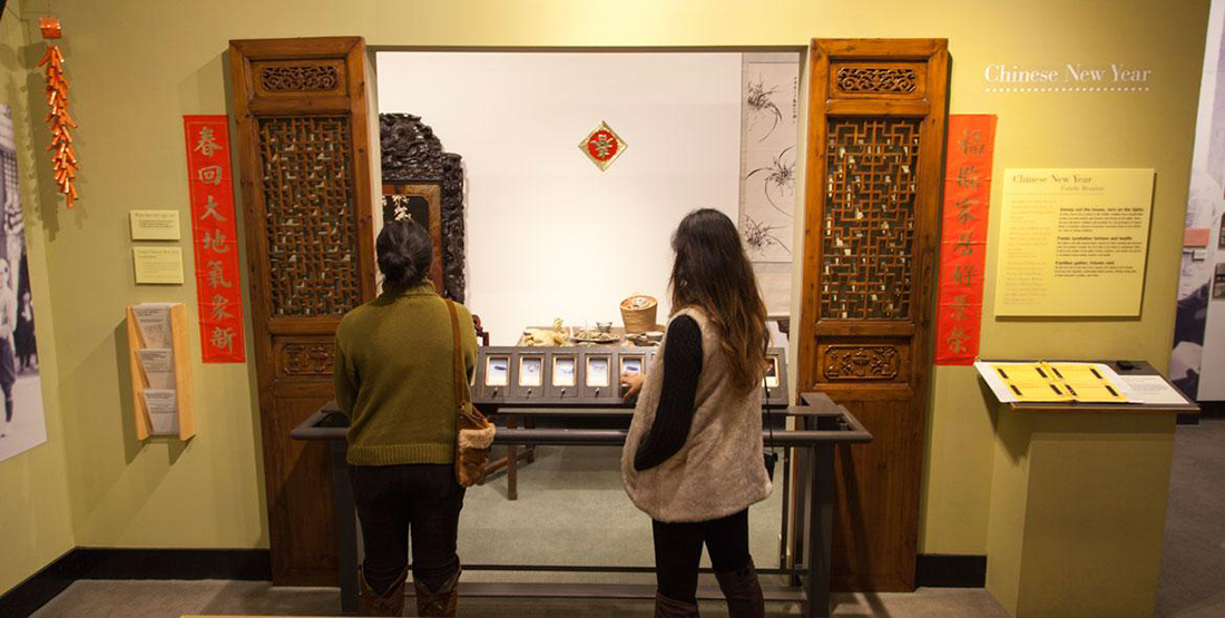 Two women view a museum display of a Chinese New Year table setting