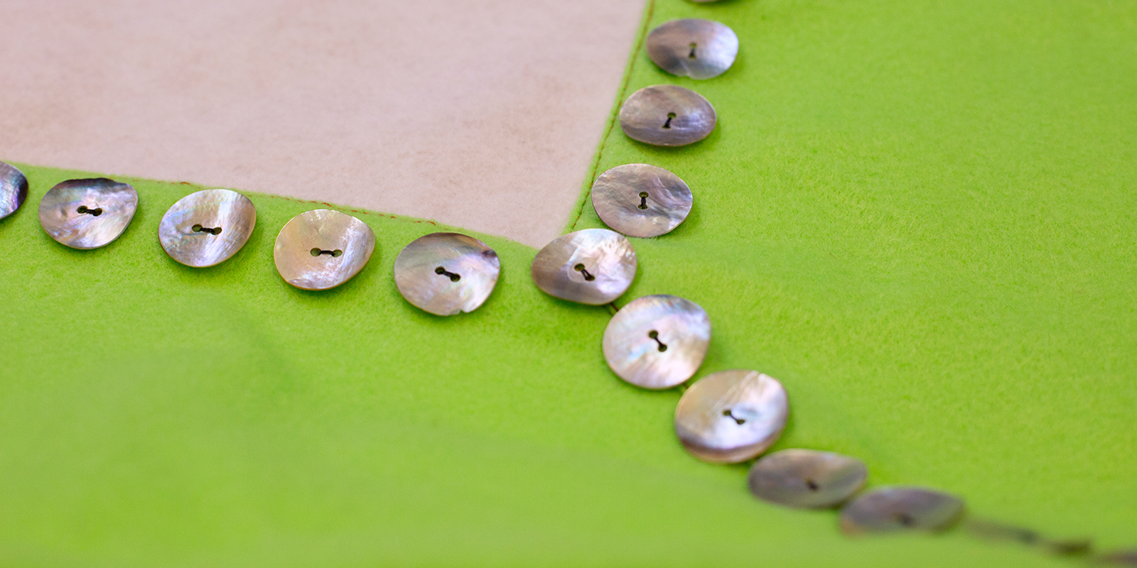 The corner of a white and green button blanket with shell button detail