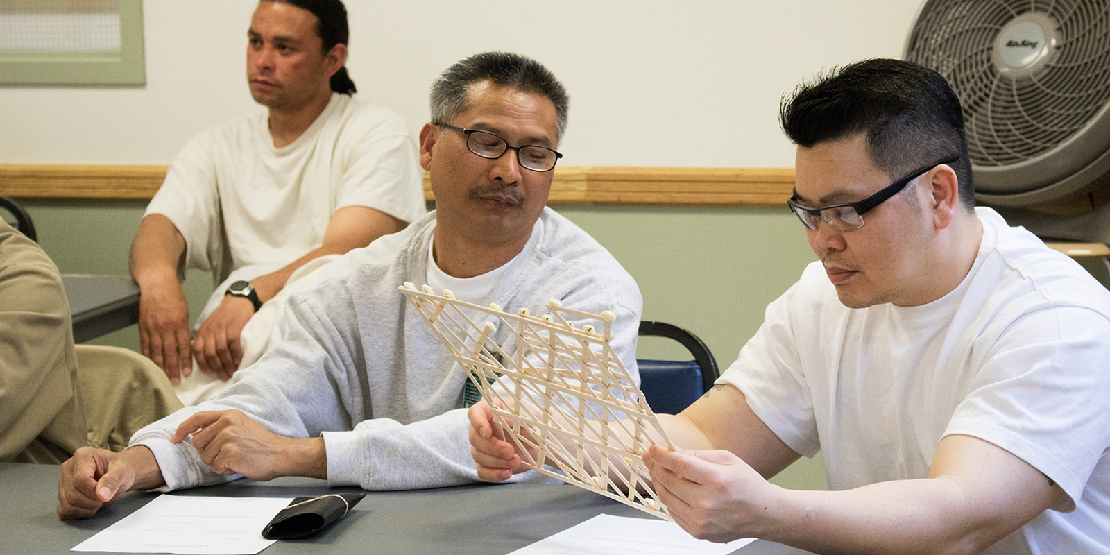 two men closely examine a stick map