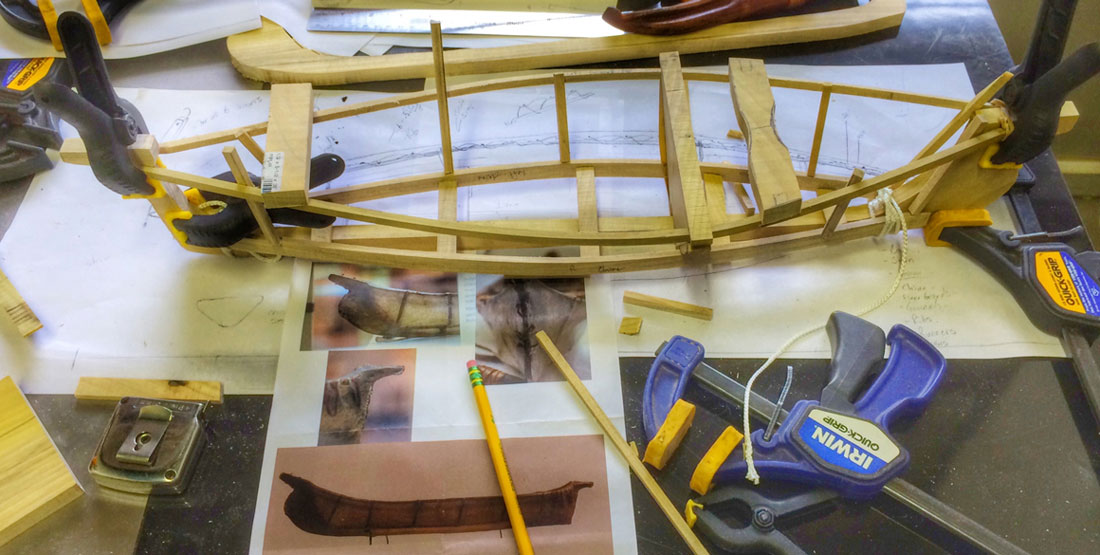 A model of the Angyaaq boat sits on the table surrounded by tools