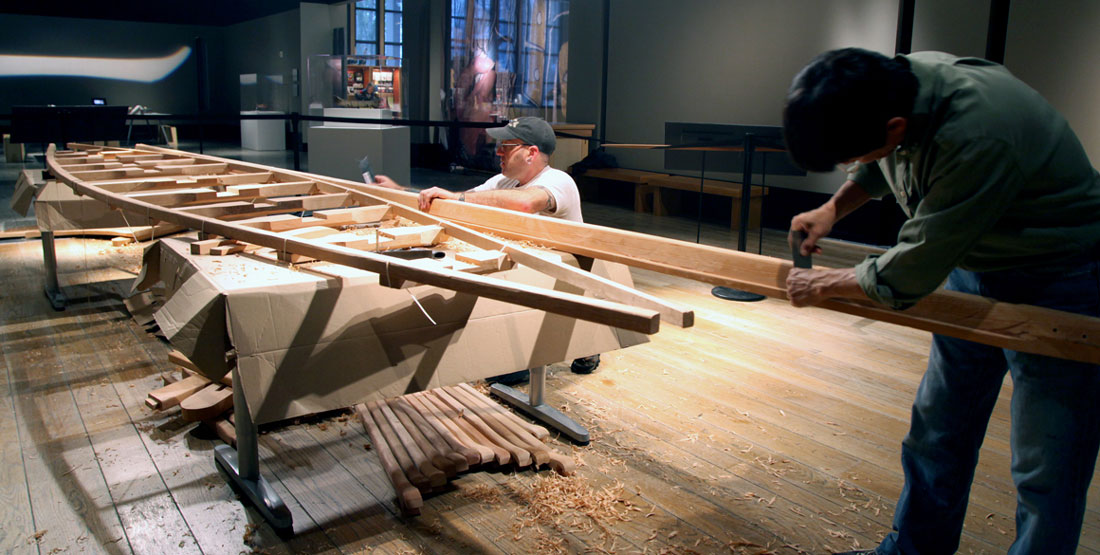 Two men work on the Angyaaq boat inside of the museum 