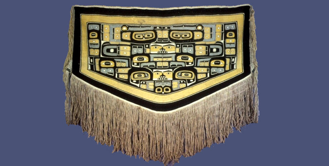 A Chilikat Dancing Blanket decorated with fringe and yellow and black and blue patterns