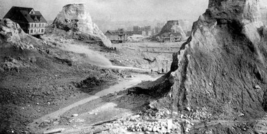 a black and white historic photo of hills being cut down in seattle