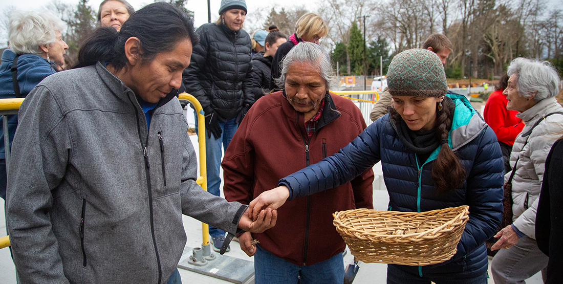 People sharing camas plant bulbs in front of the museum