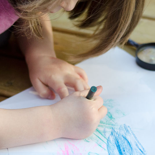 a child makes a leaf rubbing with a crayon