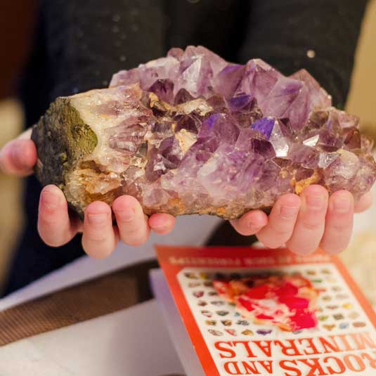 a child holds a large spiky amethyst specimen