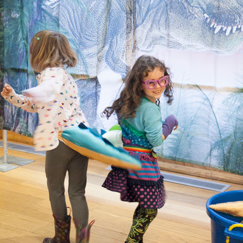 two girls wear dino tails and spin