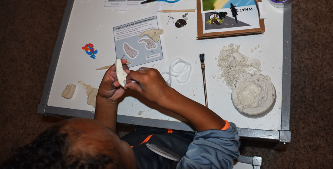 child sculpts a clay tooth 