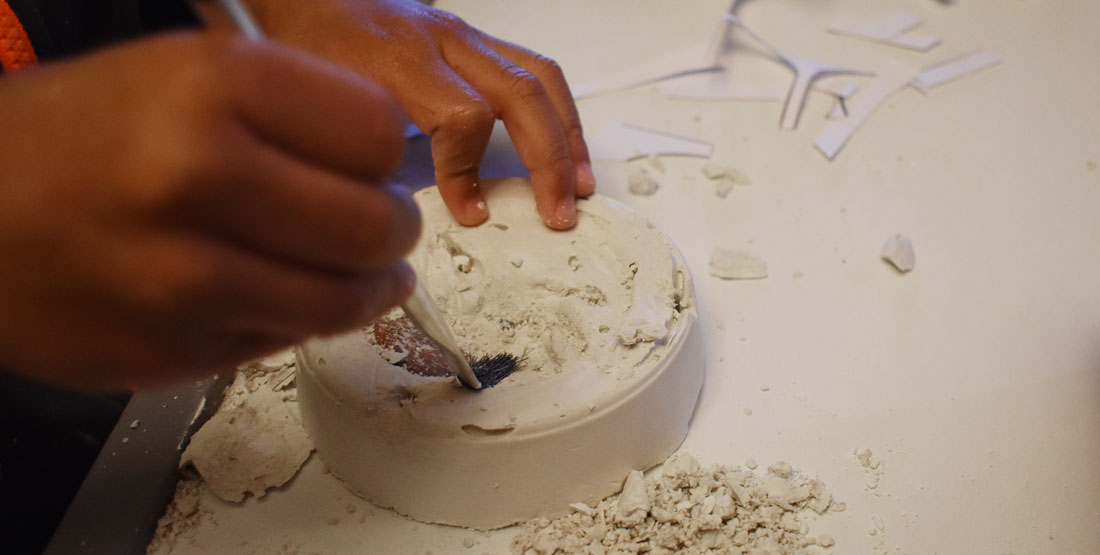 child's hand brushes matrix off of fossils