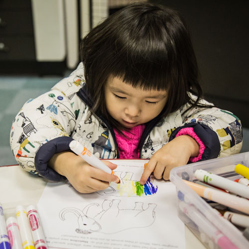 child coloring with markers in a coloring book