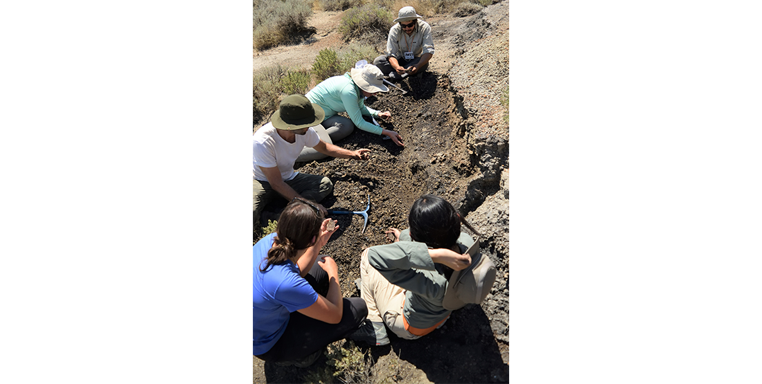 a group of participants, led by DIG Instructor Andy Tholt, hike to the top of the nearby outcrop to measure the stratigraphic positions of a layer of coal that marks the K-Pg boundary.