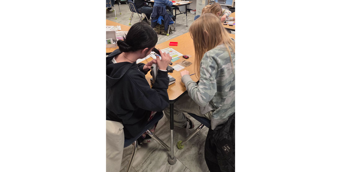 kids in a classroom look through a microscope