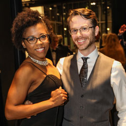 a man and a woman pose for the camera at a private event