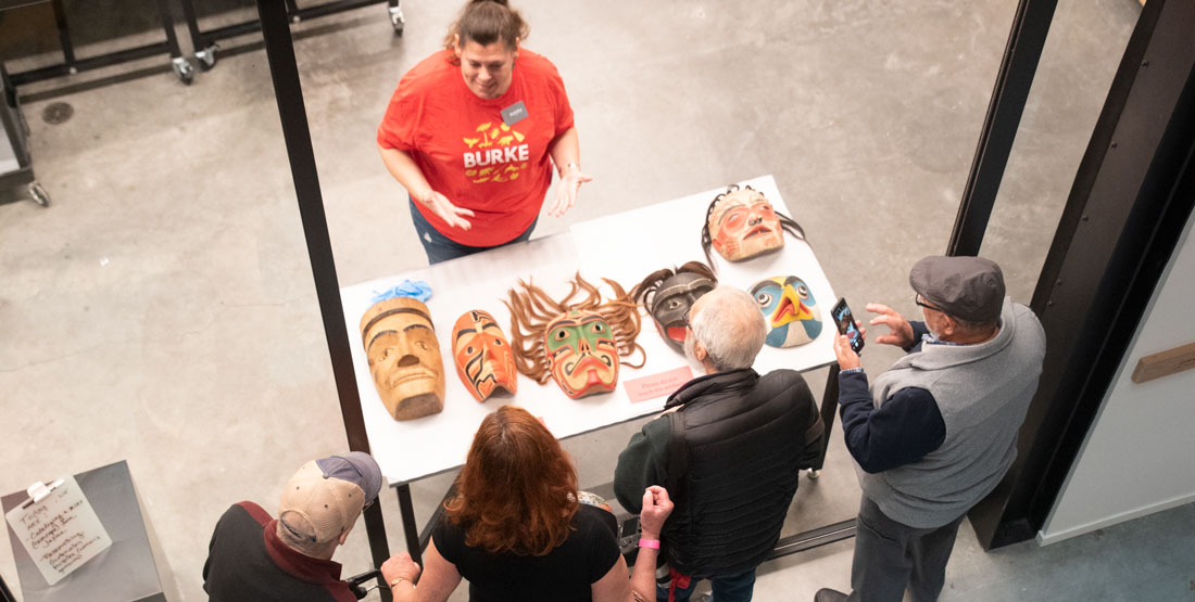 a staff member shows masks to visitors through an open door