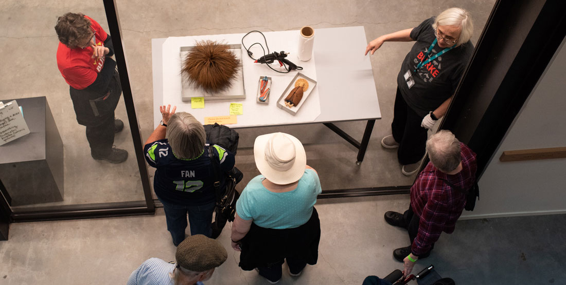 two staff members talk to visitors through an open door with objects out on a table