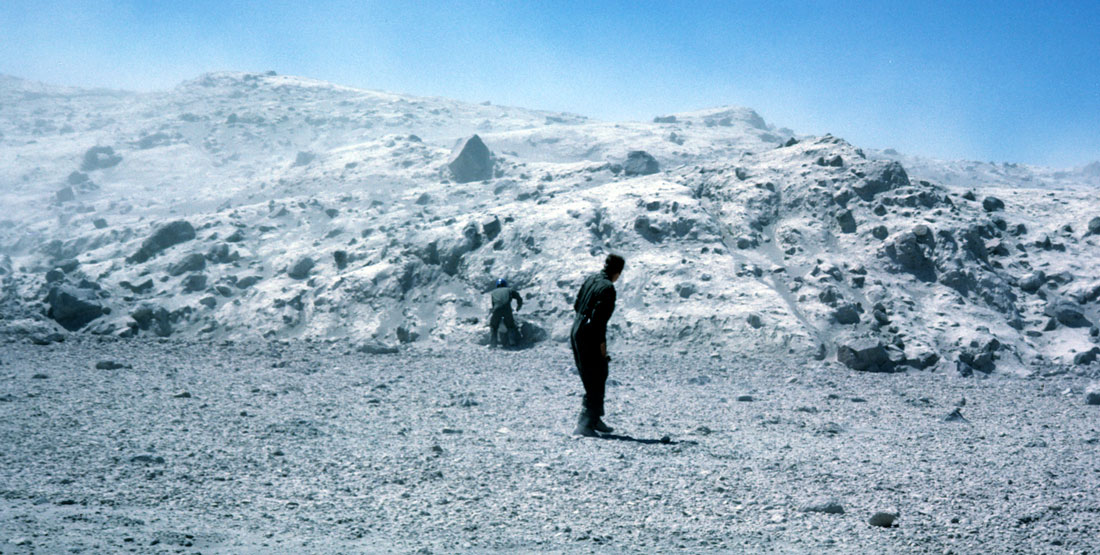 A man stands in front of a large pile of ash
