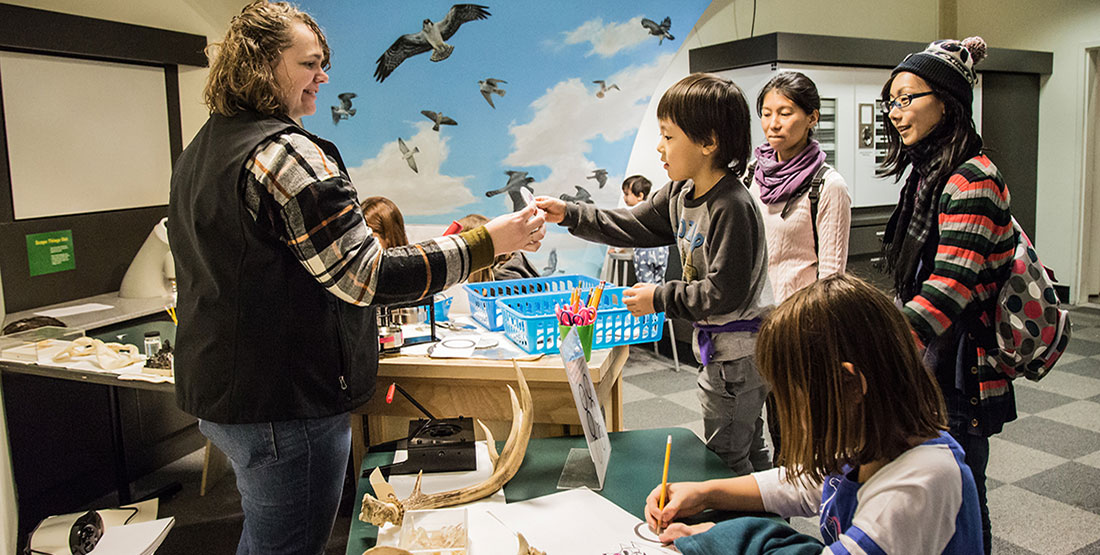 A young boy reaches for an object from a Burke educator as his family looks on