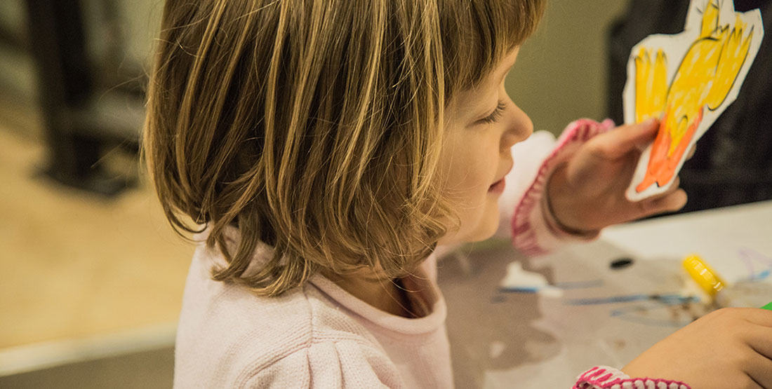 A young girl colors a yellow bird