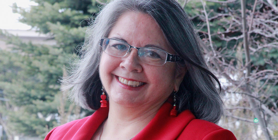 A woman wearing a red shirt smiles at the camera