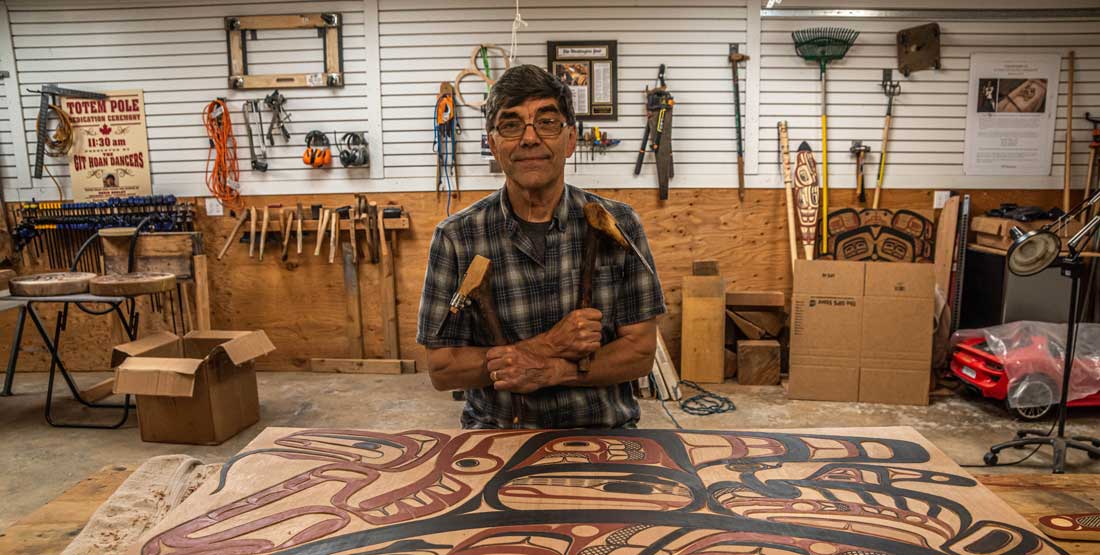 david boxley stands in his shop surrounded by carving tools