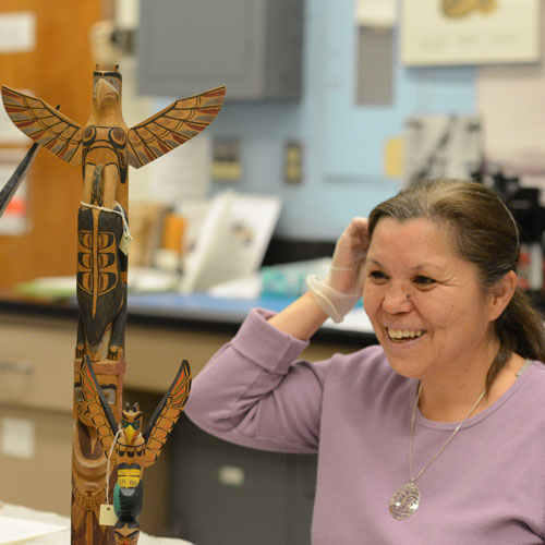 a woman smiles while admiring an object up close