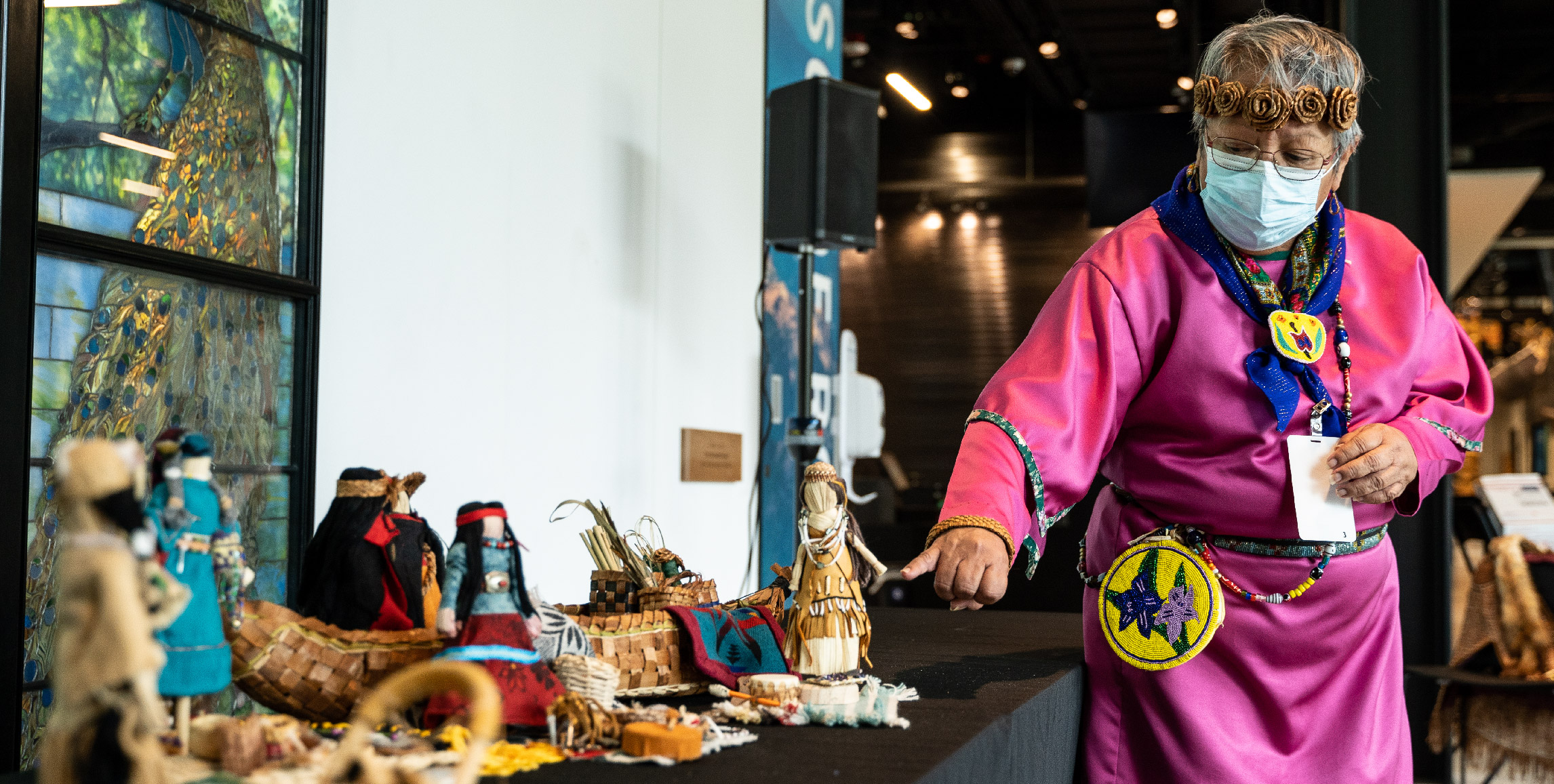 Celeste Whitewolf gestures toward cornhusk dolls.