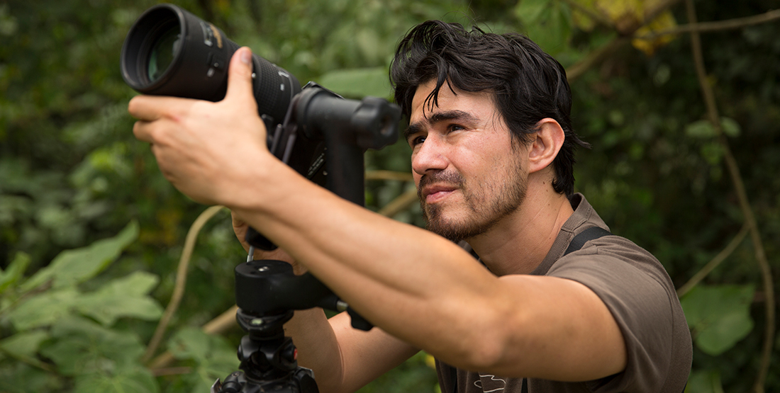 A man stands in the jungle with a large camera