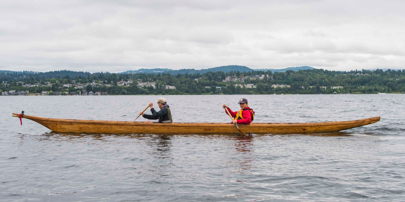two men paddle the canoe through lake washington waters