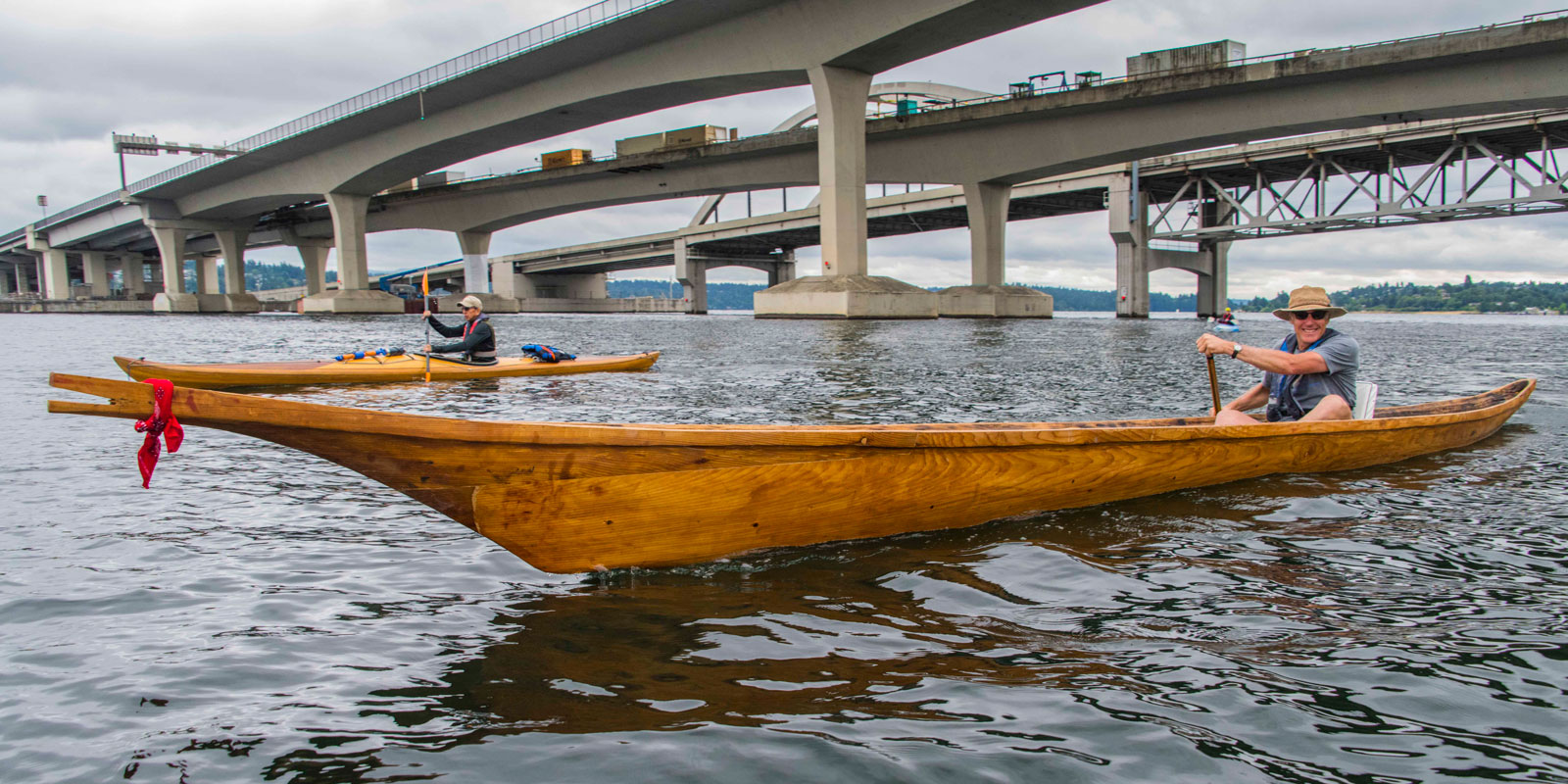 a man paddles the canoe under the bridges in lake washington