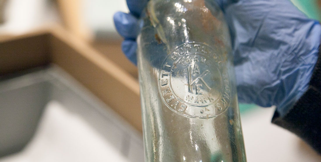 close up of an old glass bottle with words "Everett Bottling" on it