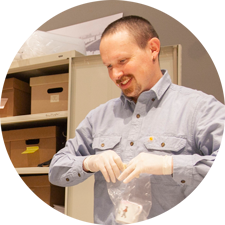 a man leans over as he pulls an artifact from a storage box