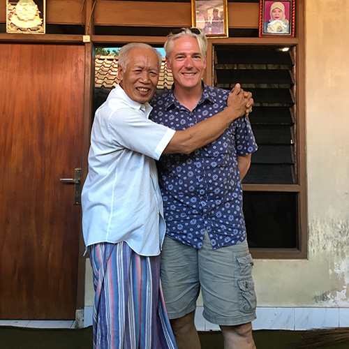 Two men stand next to each other giving each other a hug