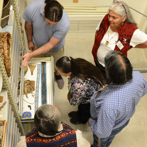 a group stands around an open drawer in the collection admiring the objects inside