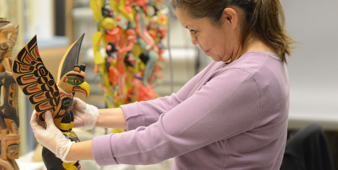 a woman holds a model totem admiring it