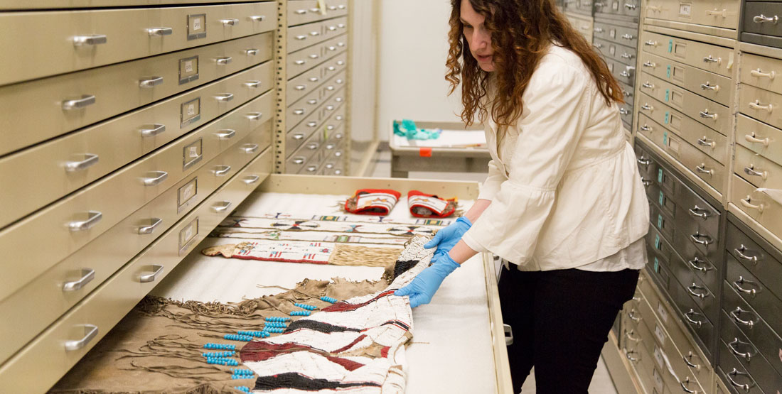 a woman pulls open a drawer in the collection revealing a beautiful beaded dress