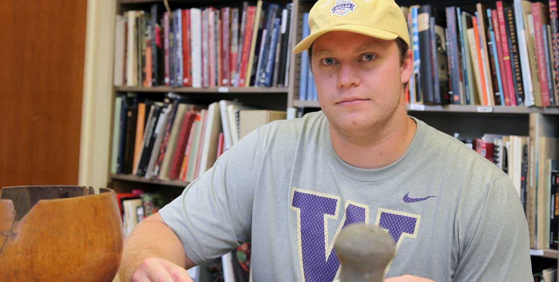 a young man poses for the camera with a husky t-shirt and baseball cap on