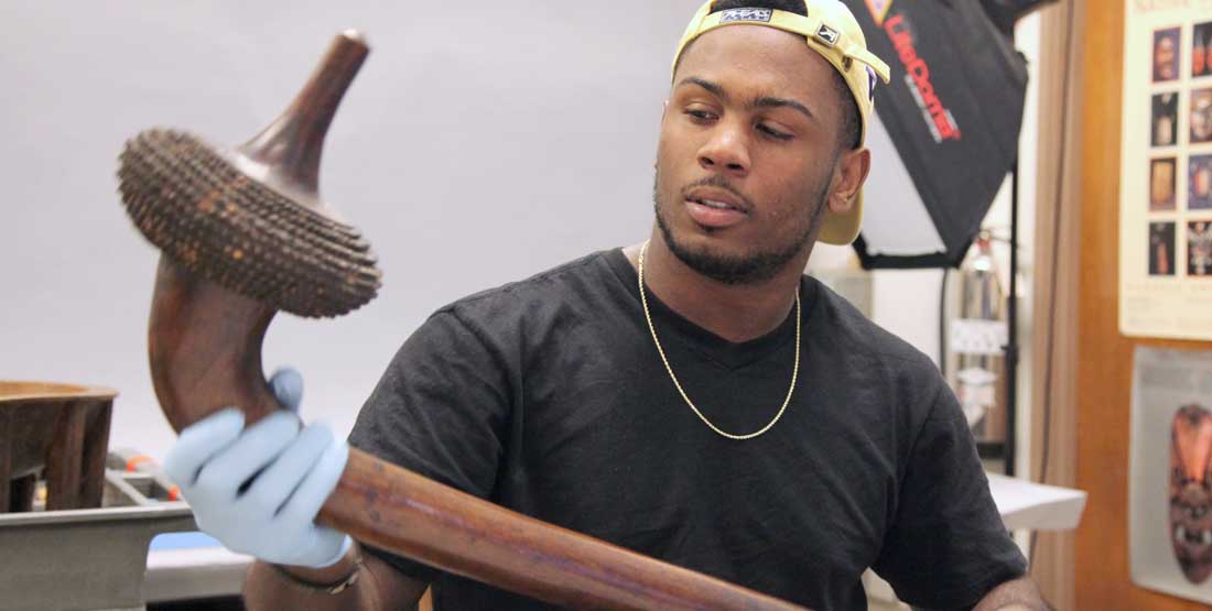 A young man examines a club in the museum collections