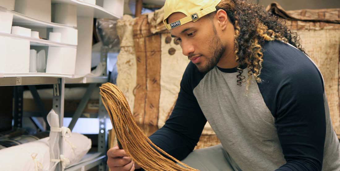 A young man closely examines a braided brush in the museum collections