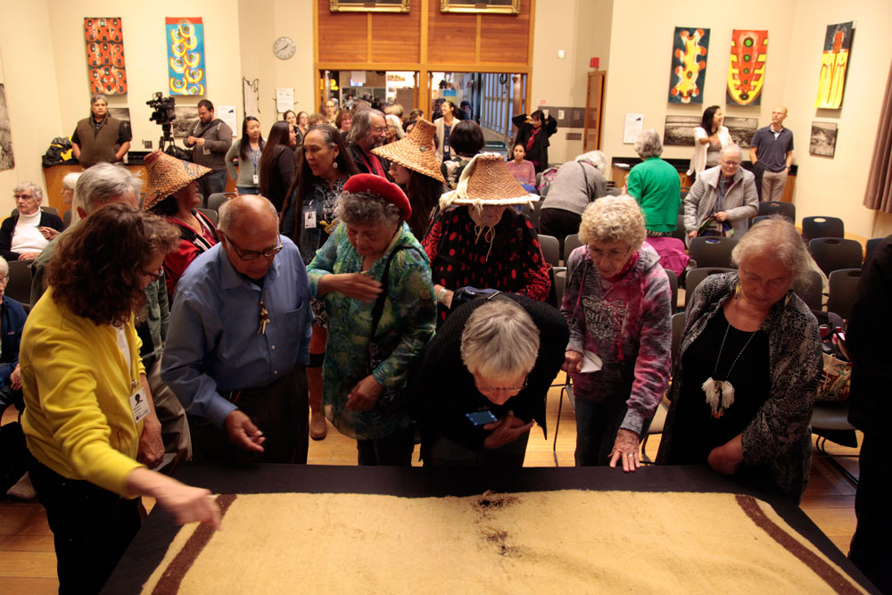 Burke Museum guests and staff examine the blanket found to contain woolly dog fur.  Photo: Burke Museum