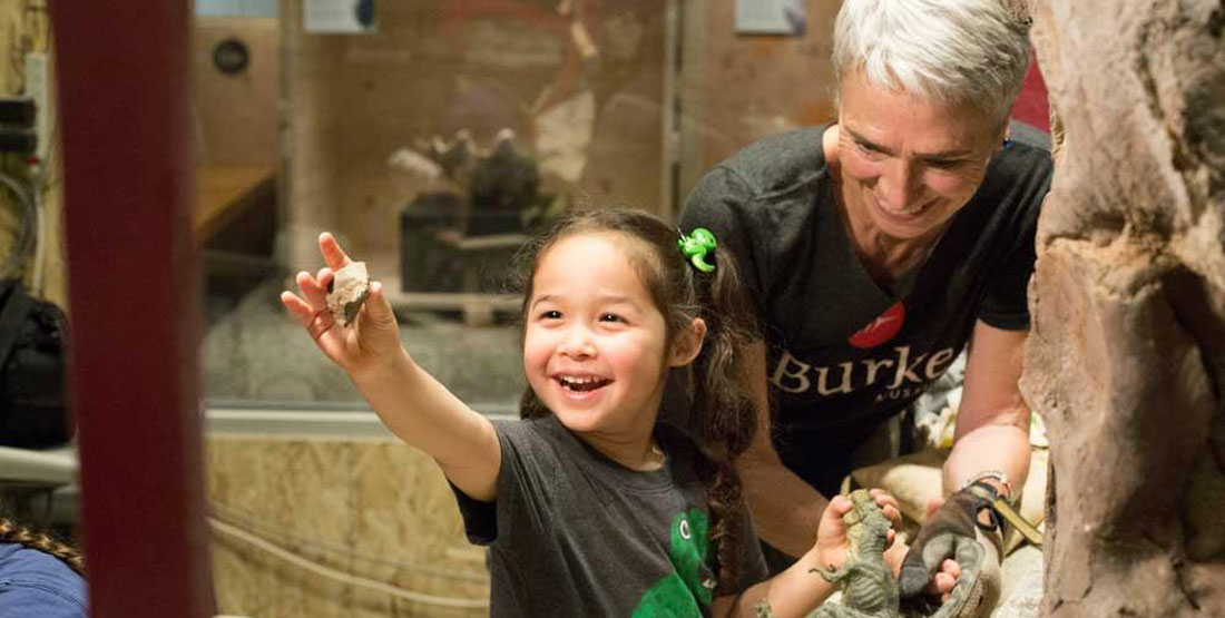 a young girl holds up a piece of rock for her mom to see