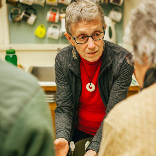 a woman speaking to two visitors