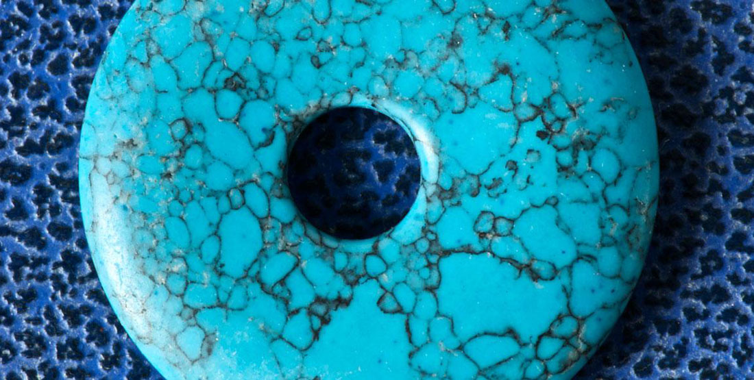 A round flat turquoise bead with a hole in the middle