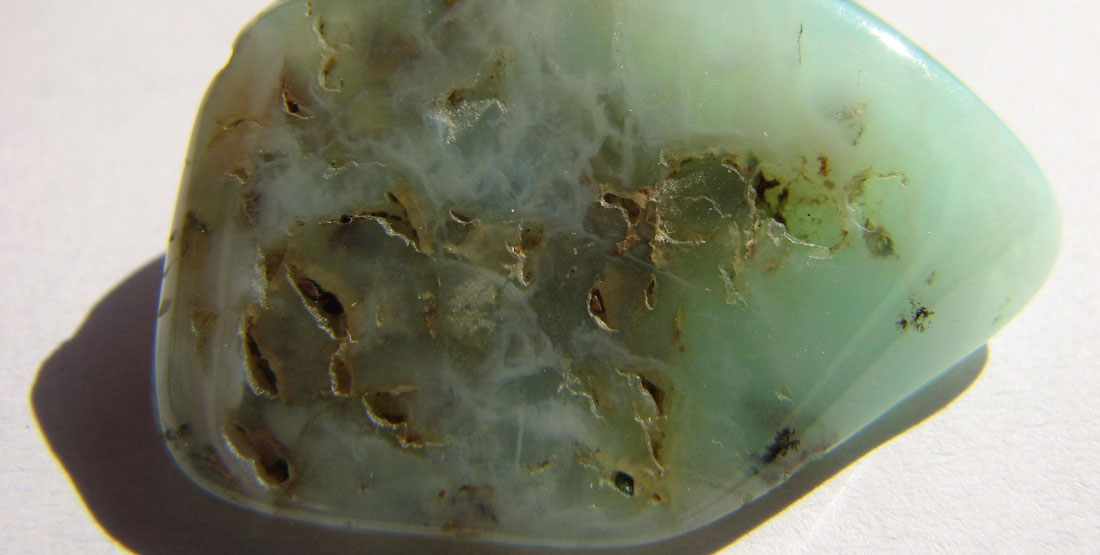 A close up view of a rough emerald with brown spots