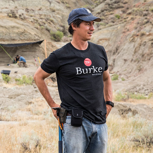 a man stands with tools on his belt and a excavation site in the background