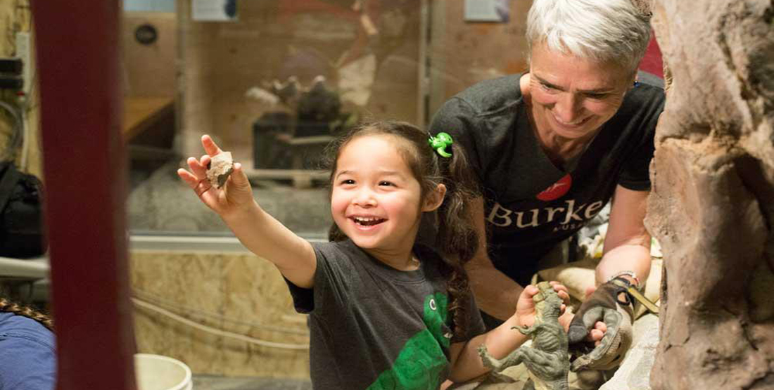 A young girl extending her arm to show her mom a piece of rock she found