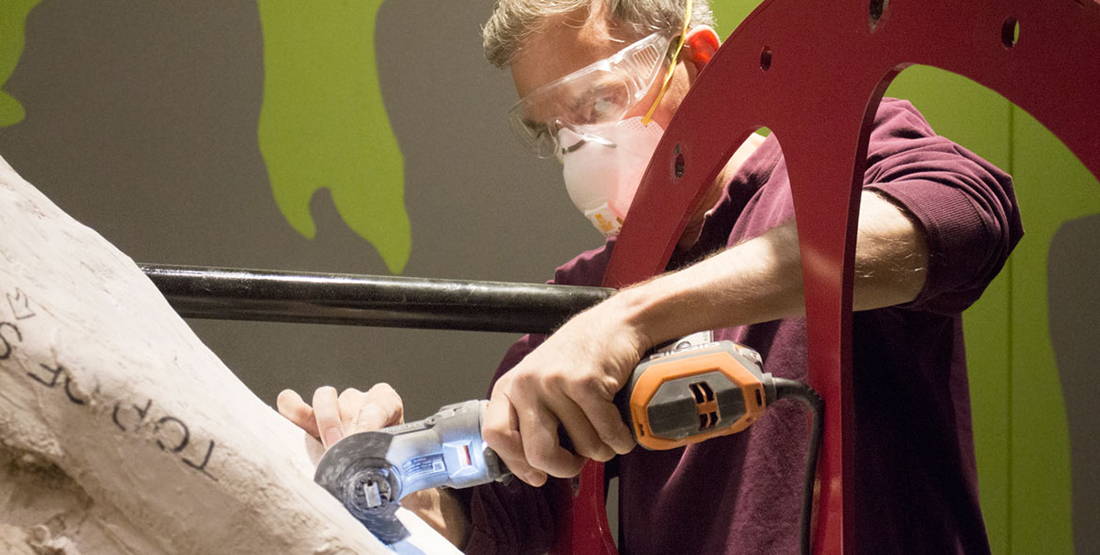 A man cuts into the plaster jacket protecting a T. rex skull