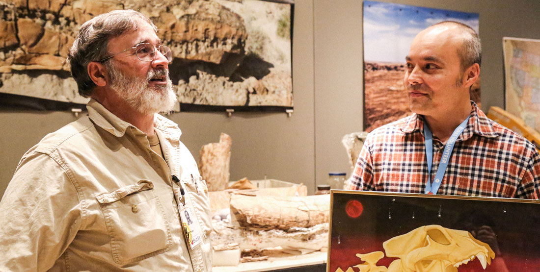 two men talking to one another in the fossil prep lab