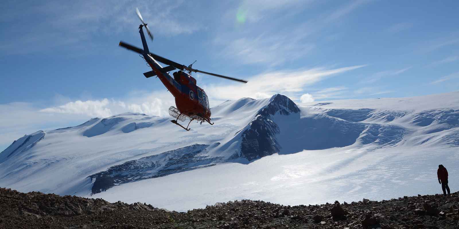 helicopter flying over frozen antarctic terrain
